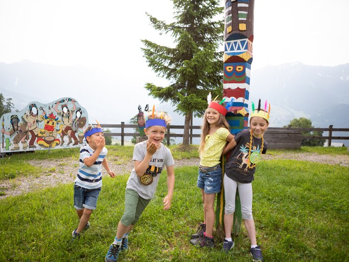 Kinder laufen um einen Totempfahl herum Bertas Kinderland Spielplätze in der Nähe vom Wolfsee in Serfaus-Fiss-Ladis in Tirol | © Serfaus-Fiss-Ladis Marketing GmbH | Andreas Kirschner