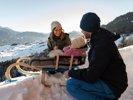 Eltern mit Kind auf Rodel Aussichtspunkt am Falterjöchl in Serfaus-Fiss-Ladis in Tirol Blog Winterwandern | © Serfaus-Fiss-Ladis Marketing GmbH | Andreas Kirschner