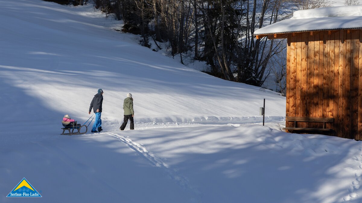 Winterwandern mit Kleinkind auf Rodel verschneite Landschaft mit Winterwanderer in Serfaus-Fiss-Ladis | © Serfaus-Fiss-Ladis Marketing GmbH | Andreas Kirschner