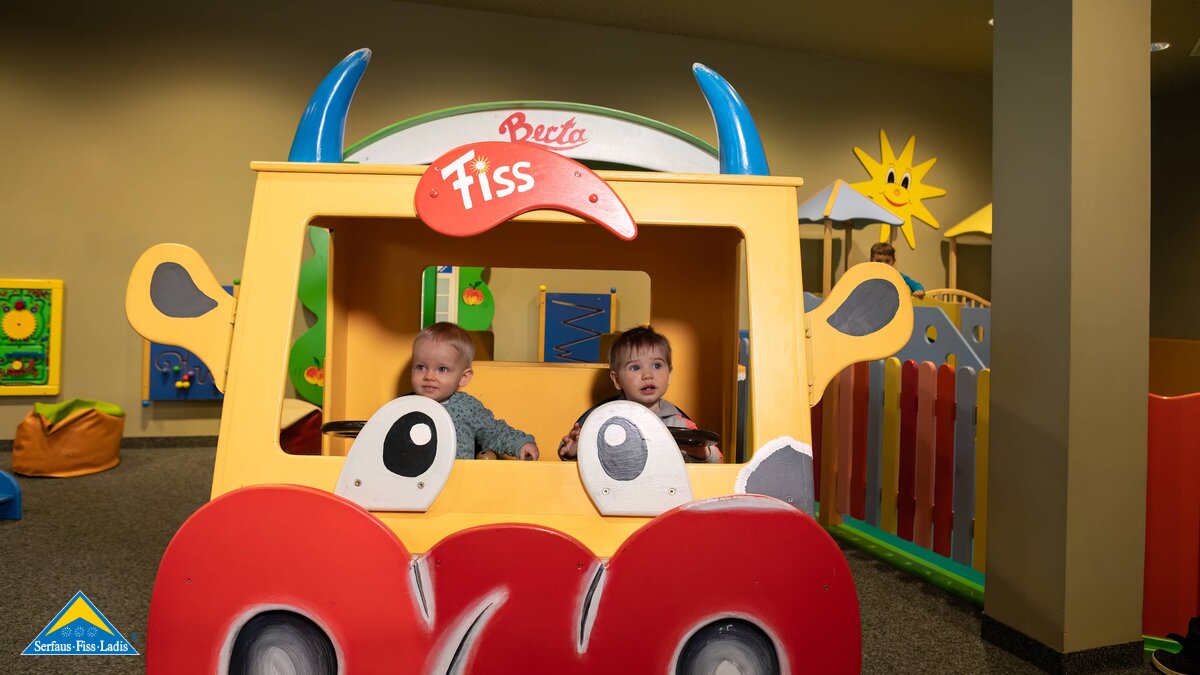 Zwei Mädchen sitzen in der Flotten Berta Maskottchen indoor spielen bei Schlechtwetter im Winterurlaub mit Kleinkindern Familienregion Serfaus-Fiss-Ladis in Tirol | © Serfaus-Fiss-Ladis Marketing GmbH | Andreas Kirschner